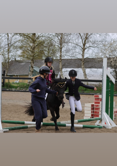 en pony med rytter over lille spring og 2 hjælpere 